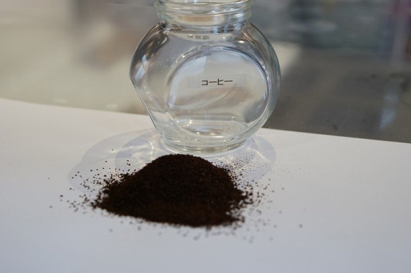 サカンライブラリー画像5　瓶入り素材サンプル　顆粒状コーヒー骨材　机の上に広げたコーヒー材料　黒に近いこげ茶系の色　Coffee bean