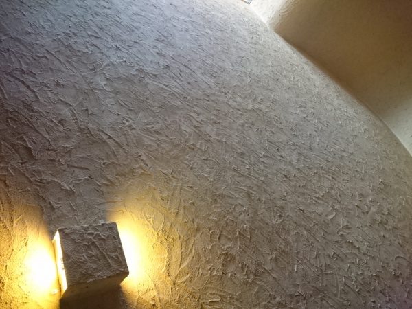 土壁風左官仕上げの壁、左下に明かりがある