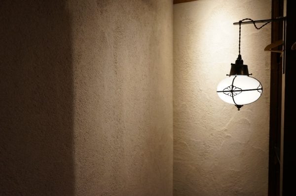 飲食店に施工した原田左官オリジナル素材「空 - KUU」の壁と横に照明器具