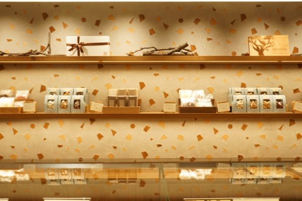 木片入りのモラート仕上げの壁、棚にはチョコレートショップの商品が並んでいる
