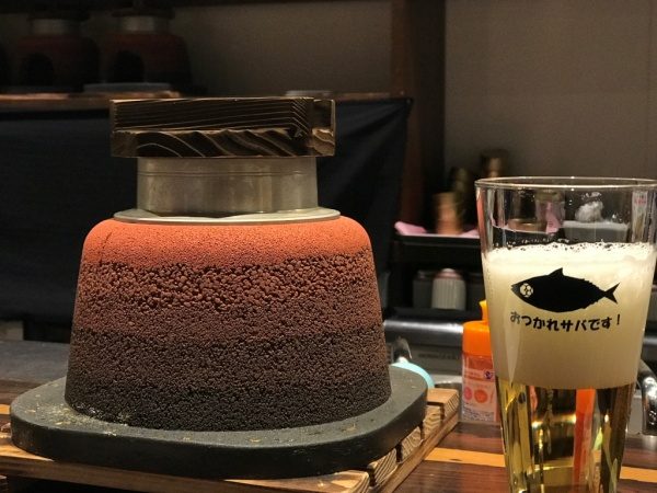 赤の版築かまど、横にビールが注がれたコップ、SABAR+ 大阪京橋店