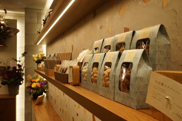 文京区西片のDRYADES店内、木片を入れたモラート仕上げの壁と商品棚、商品や花が並んでいる