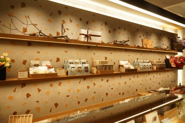 木片+モラート仕上げの壁と商品棚、棚には商品や花が並んでいる、左側アングル画像