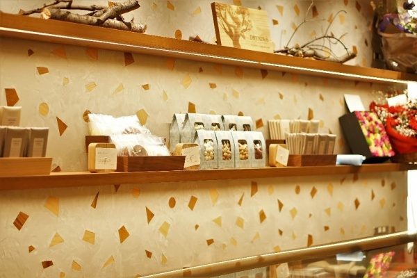 木片+モラート仕上げの壁と商品棚、棚には商品や花が並んでいる、左側アングルアップめの画像