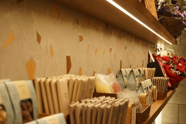 木片+モラート仕上げの壁と商品棚、棚には商品や花が並んでいる、左側アングル壁のアップ画像