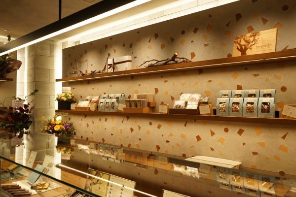 木片+モラート仕上げの壁と商品棚、棚には商品や花が並んでいる、右側アングル画像
