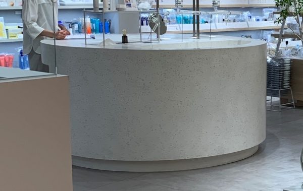 ビールストーンの白・寒水石で施工した円形型ディスプレイ台、完成して化粧品店内に設置した状態、台上には商品がある
