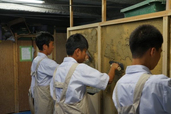 塗り体験で板に塗りつけている中学校の生徒さん達