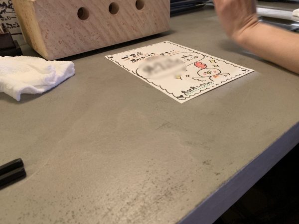 モールテックスグレーのカウンターテーブル。恵比寿の飲食店。挨拶カードがある