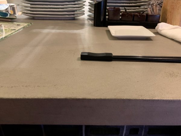 モールテックスグレーのカウンターテーブル。恵比寿の飲食店。お箸と箸置きやお皿などがある