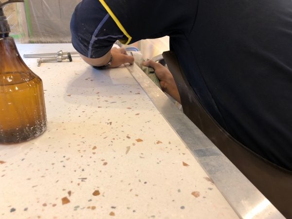 ビールストーンのカウンター小口部分にアルミバーを当ててラインを出し仕上げている