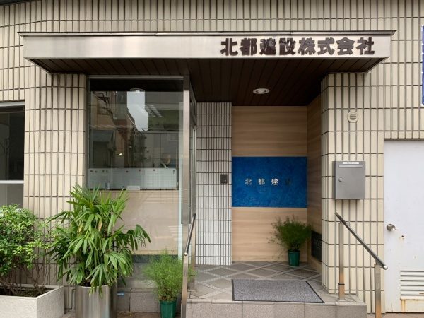 北都建設様エントランス施工完成。樹脂系左官材のブルー、白２色で施工し切り文字が付いた状態