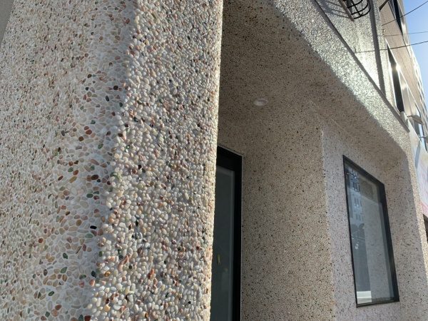 原田左官タイルライブラリーの外壁。洗い出しネットストーンで施工。太陽に照らされてキラッと光っている