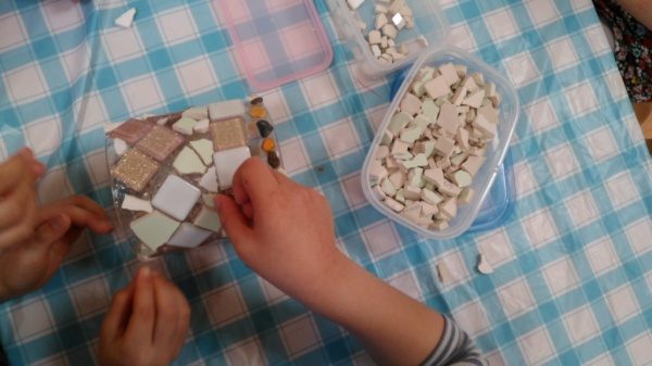 本駒込こどもヶ丘保育園の卒業制作タイル。タイルをコップに貼り付けている様子