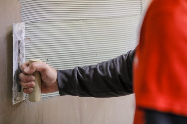 壁に鏝でタイル張り付け材を塗る様子