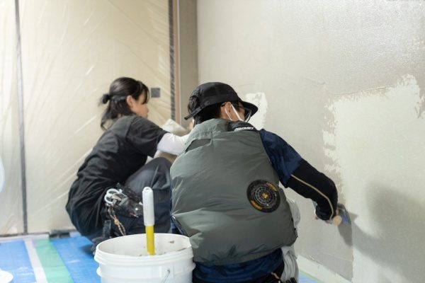 女性と男性二名の左官職人さんが壁を塗っている