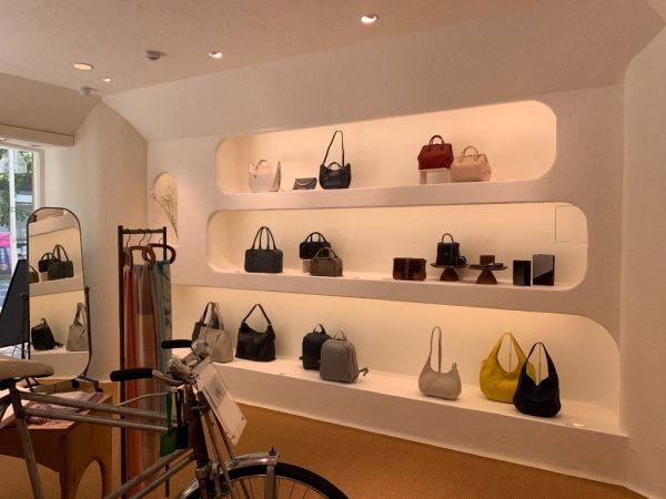 マザーハウス銀座店の内装。原田左官施工の漆喰。店内にバッグがディスプレイされており、自転車も置かれている