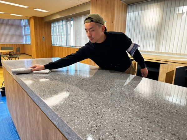 グレーダルメシアン色のビールストーンにトップコート塗布する左官職人さん