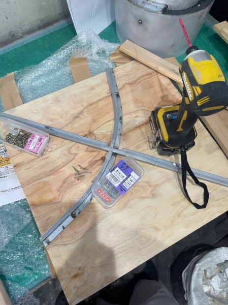 木工下地用の木板と弓矢のような形状の金物と工具