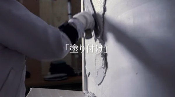 左官鏝で壁に左官材料を塗りつける様子