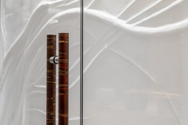 オフィスエントランスホールの壁に施工した原田左官オリジナル漆喰「フルーフレ」の壁。桜の木をイメージした模様のアートウォール